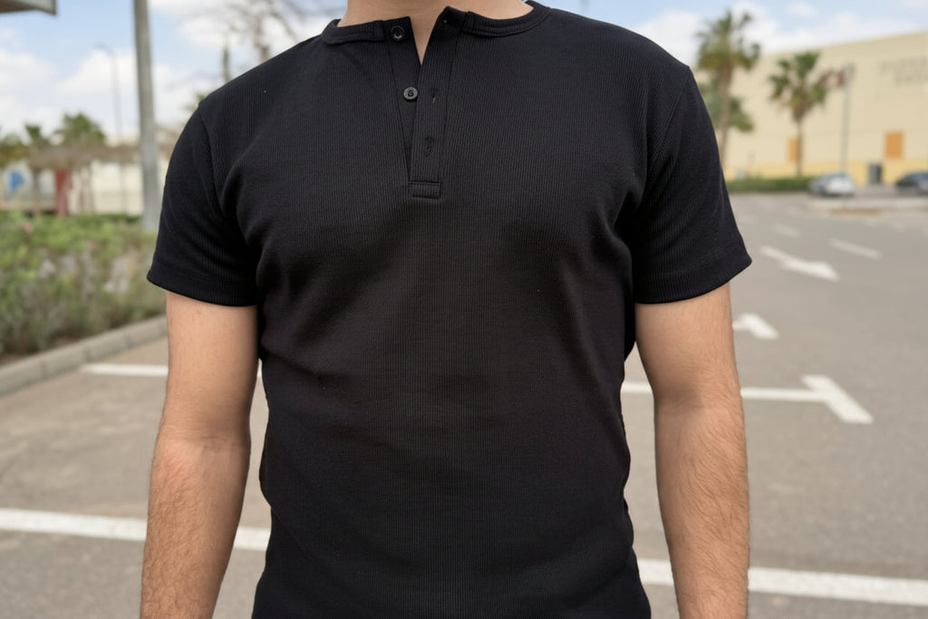 Person wearing a black polo shirt standing on a street.