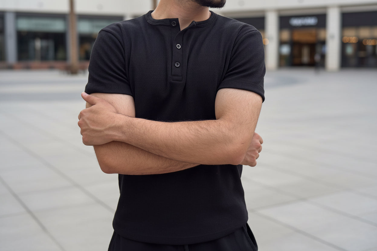 Person wearing a black shirt with arms crossed in an outdoor setting
